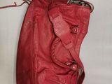 red leather handbag on a white background with a strap