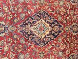 an antique persian rug with a red background and blue and yellow medallions