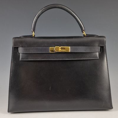 un sac à main en cuir noir avec des ferrures dorées sur la poignée