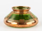 un vase en verre vert bordé d'or, posé sur un fond blanc