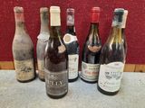 Plusieurs bouteilles de vin sont alignées sur une table devant un mur rouge