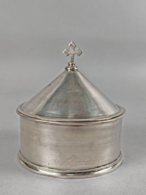 une boîte plaquée argent avec un couvercle et une croix sur le dessus