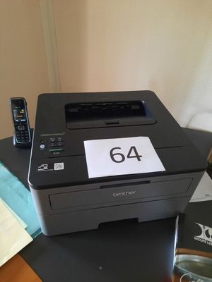 une imprimante noire posée sur un bureau, à côté d'un téléphone portable