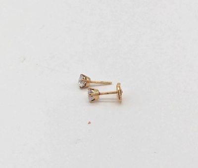 un gros plan sur une paire de boucles d'oreilles en or sur une surface blanche