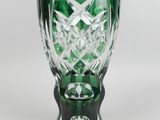 vase en verre vert posé sur une surface blanche, avec un fond blanc