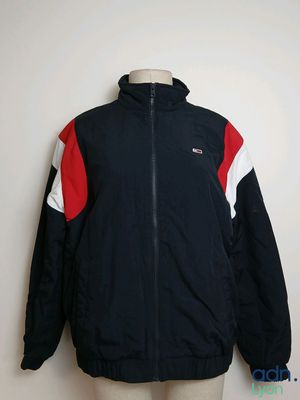 La veste est noire, rouge et blanche, avec une rayure rouge et blanche.