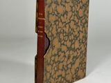 an old book with a brown cover sitting on top of a white table
