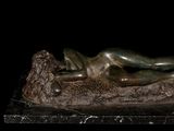 statue of a woman laying on a rock on a black background