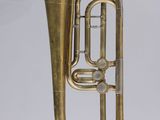 On voit un vieux tuba en laiton sur fond blanc.