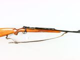 an old rifle with a wooden barrel and a sling on a white surface