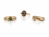 trois bagues en or ornées d'émeraudes et de diamants sur fond blanc