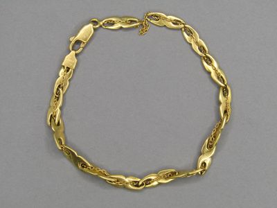 gros plan d'un bracelet en or sur une surface grise