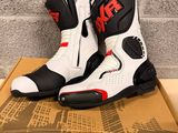 the pair of white and black motorcycle boots are on top of a cardboard box
