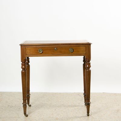 Petite table en acajou. Un tiroir. Dessus de cuir. Pieds tou…
