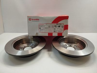 une paire de disques de frein posés sur une surface blanche, à côté d'une boîte