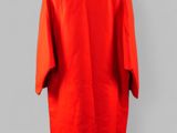 a red dress hanging on a hanger against a gray wall