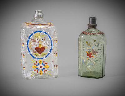 two glass bottles with designs on them on a gray background
