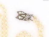 two pearl necklaces and a broocher with a leaf