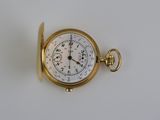 une montre de poche en or sur une surface blanche