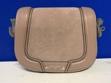 un sac à main en cuir beige muni d'une poignée en métal, posé sur une table blanche