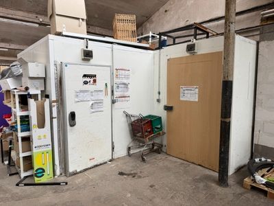 une photo d'une pièce dans laquelle se trouve un réfrigérateur