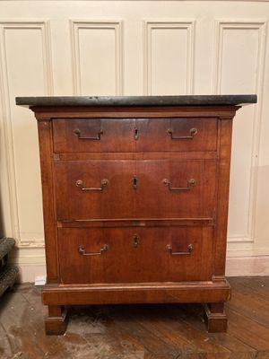 une vieille commode en bois avec un plateau en marbre, posée sur un parquet en bois massif
