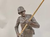 bronze statue of a soldier holding a flag on top of a table