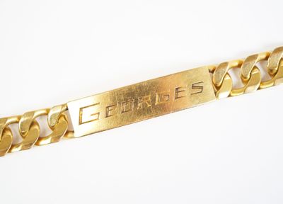une photo en gros plan d'un bracelet en or muni d'une plaque portant un nom