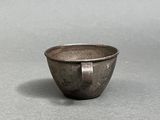 an old metal bowl sitting on top of a gray surface