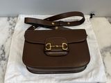 the brown leather bag is sitting on top of a white cloth