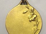 a close up of a gold medal with a flower on it