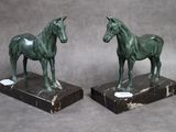 une paire de statues de chevaux en bronze sur des socles en marbre, sur fond gris