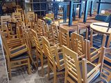 Des tables et des chaises sont alignées dans une pièce dont les étagères regorgent de bouteilles de vin