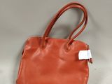 an orange leather handbag with a tag on it