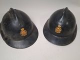 pair of black helmets with gold emblems on them sitting on a white surface