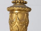 a gold vase with a candle on top of it