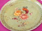 a green plate with flowers on it on a pink table