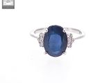 a close up of a ring with a sapphire and diamonds