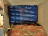 many books in a box that are stacked on top of each other