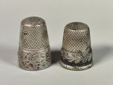 une paire de dés à coudre en argent posés sur une surface blanche, sur fond blanc