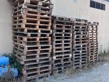 une pile de palettes posée à l'extérieur d'un bâtiment, à côté d'un fût bleu