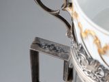 a silver and white cup with a handle on a table
