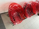 several red baskets lined up against a white wall on a tiled floor