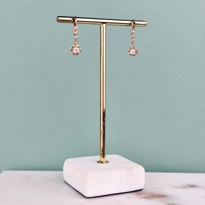 une paire de boucles d'oreilles posée sur un présentoir, sur un comptoir en marbre