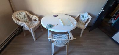 une table et des chaises blanches dans un coin de la pièce