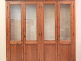 un grand meuble en bois avec des portes en verre dans une pièce