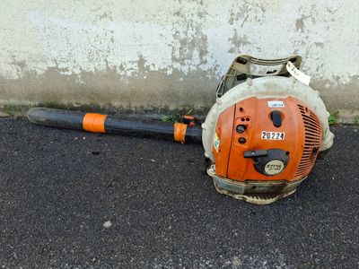 a small blower sitting on the ground next to a concrete wall