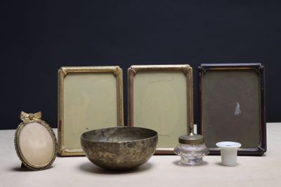 trois cadres et un bol posés sur une table à côté d'une bougie