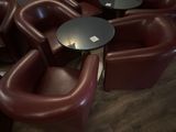 de nombreuses chaises et tables dans une pièce où est accrochée une horloge au mur