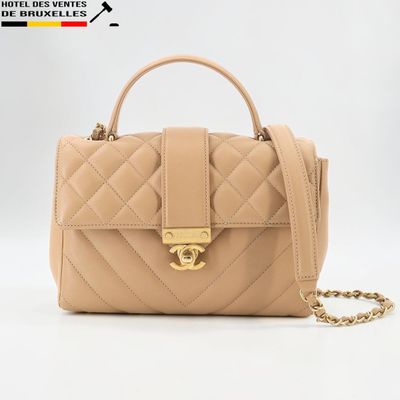 un sac à main beige muni d'une bandoulière en chaîne et d'un fermoir doré